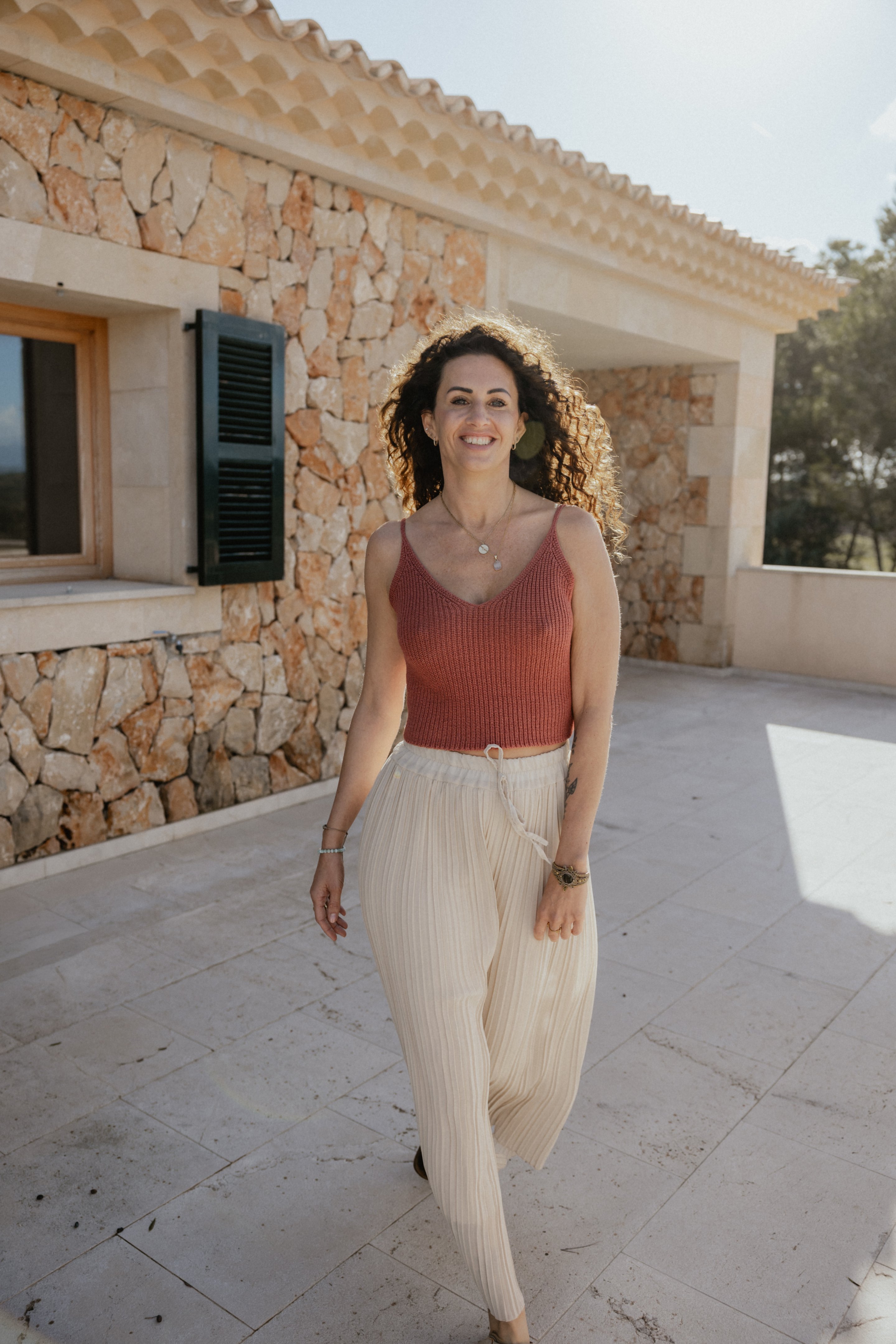Janina Däubel auf einer mediterranen Terrasse, in entspannter Pose – Gründerin von Facettenreich