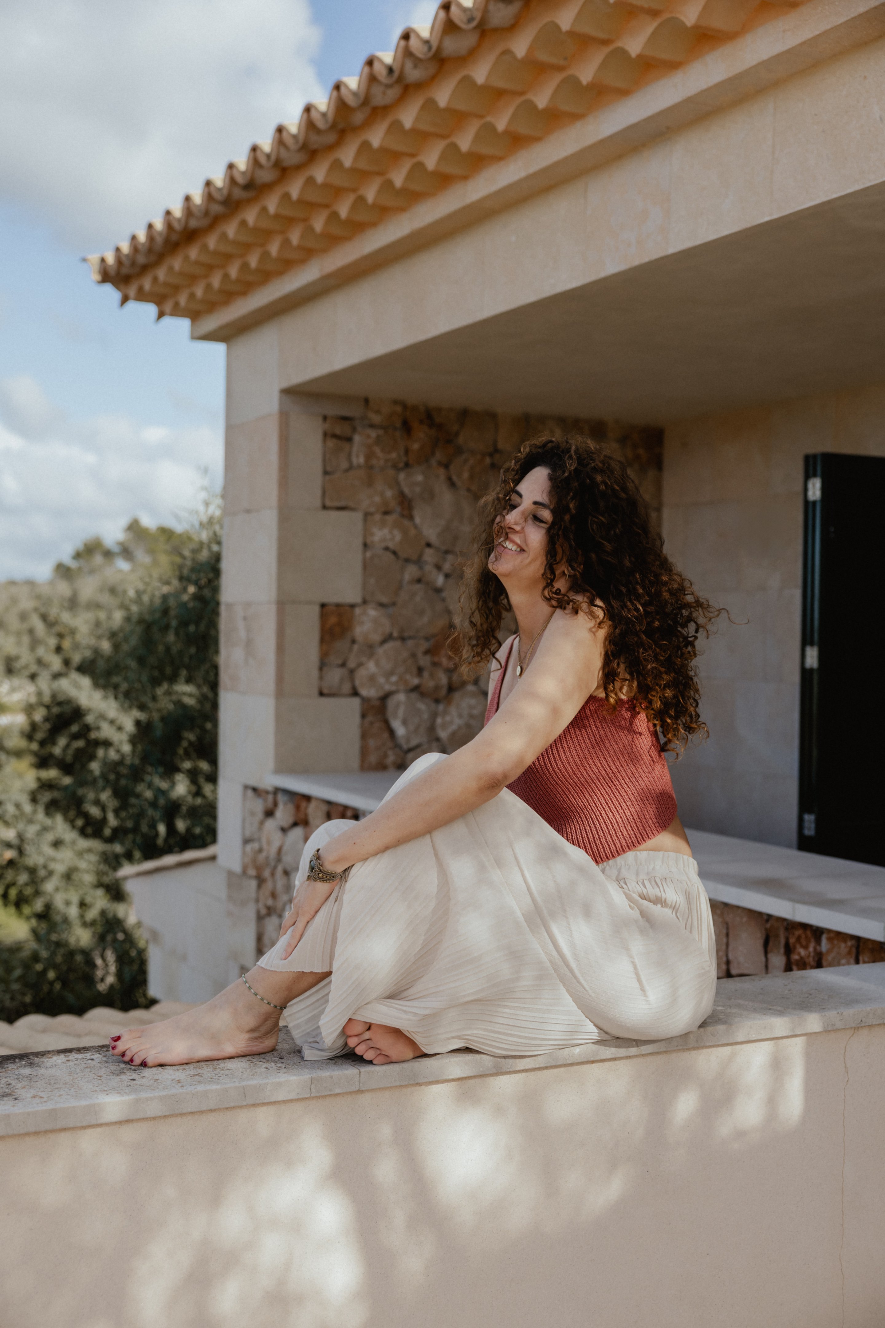 Janina Däubel, Gründerin von Facettenreich, lächelnd auf einer mediterranen Terrasse